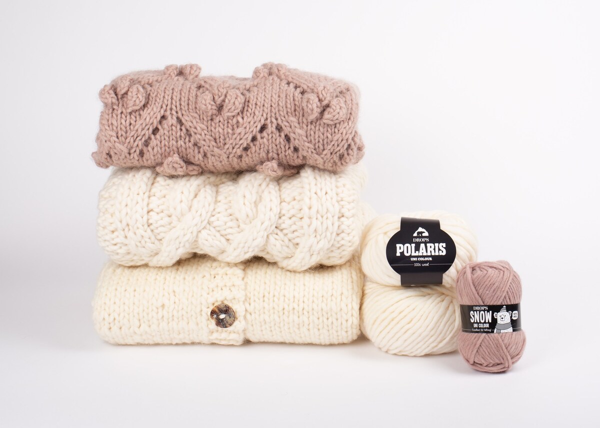 Foldet kabelstrik med Polaris og Snow; varme rosa og cremefarvede toner.